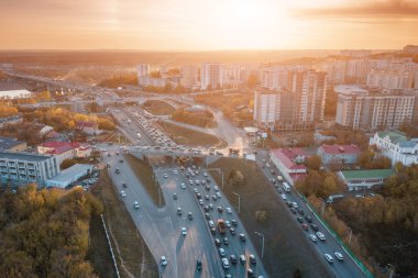 Şehir kavşağı ve üst geçitleri gün batımında trafik havası manzaralı. Yoğun şehir konseptinde ulaşım