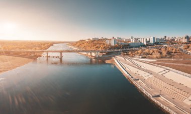 Köprü ve işlek şehir caddesi büyük bir nehrin seti boyunca uzanır.