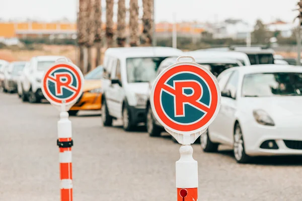 A sign prohibiting parking and stopping cars near the entrance to the shopping center. Lots of rule-breaking cars in the background