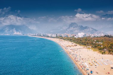 Antalya tatil köyündeki popüler ve manzaralı Konyaalti plajı manzarası. Arka planı sisli görkemli dağlar. Türkiye 'de tatil ve tatil