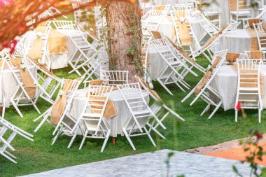 A lot of tables and attached chairs are waiting for a special event or a wedding celebration outdoors