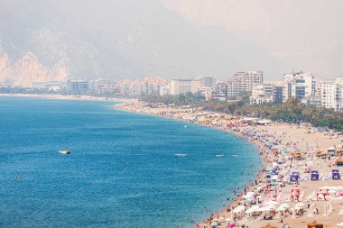04 June 2022, Antalya, Turkey: Crowded city beach with hundreds of vacationers and tourists resting, sunbathing and swimming at extremely hot summer day in resort town