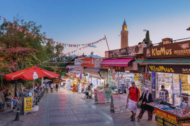 21 June 2022, Antalya, Turkey: Tourist walking and shopping in old town bazaar with view of Yivli minaret at sunset