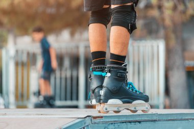 Close-up of the legs of a roller skater performing tricks and just riding on the ramp in urban sports park. Teenage hobby concept
