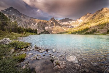 Panoramic morning view of famous natural attraction - the Krepkoe Lake at sunrise with illuminated mountain peaks. National park and hiking concept