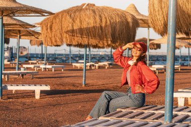A happy and fashionable girl enjoys a weekend at the resort with umbrellas and sun beds at low season