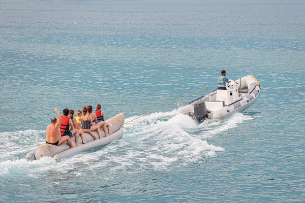 09 January 2022, Hurghada, Egypt: Tourists and vacationers have fun on an inflatable banana tied to a speed boat. Sea activities and recreation