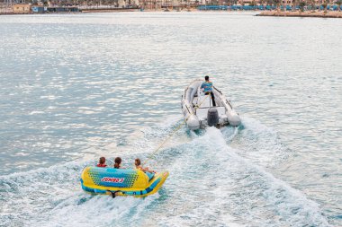 09 January 2022, Hurghada, Egypt: Tourists and vacationers have fun on an inflatable banana tied to a speed boat. Sea activities and recreation