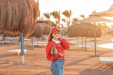 A happy and fashionable girl enjoys a weekend and walking at the resort with umbrellas and sun beds at low season