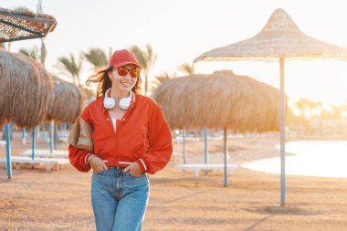 A happy and fashionable girl enjoys a weekend and walking at the resort with umbrellas and sun beds at low season
