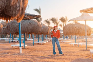 A happy and fashionable girl enjoys a weekend and walking at the resort with umbrellas and sun beds at low season