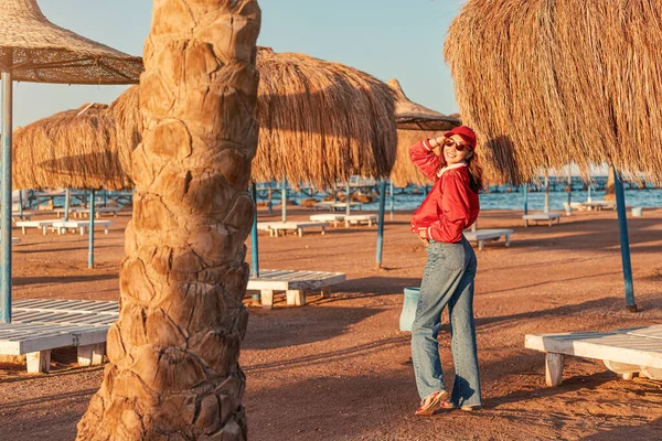 A happy and fashionable girl enjoys a weekend at the resort with umbrellas and sun beds at low season