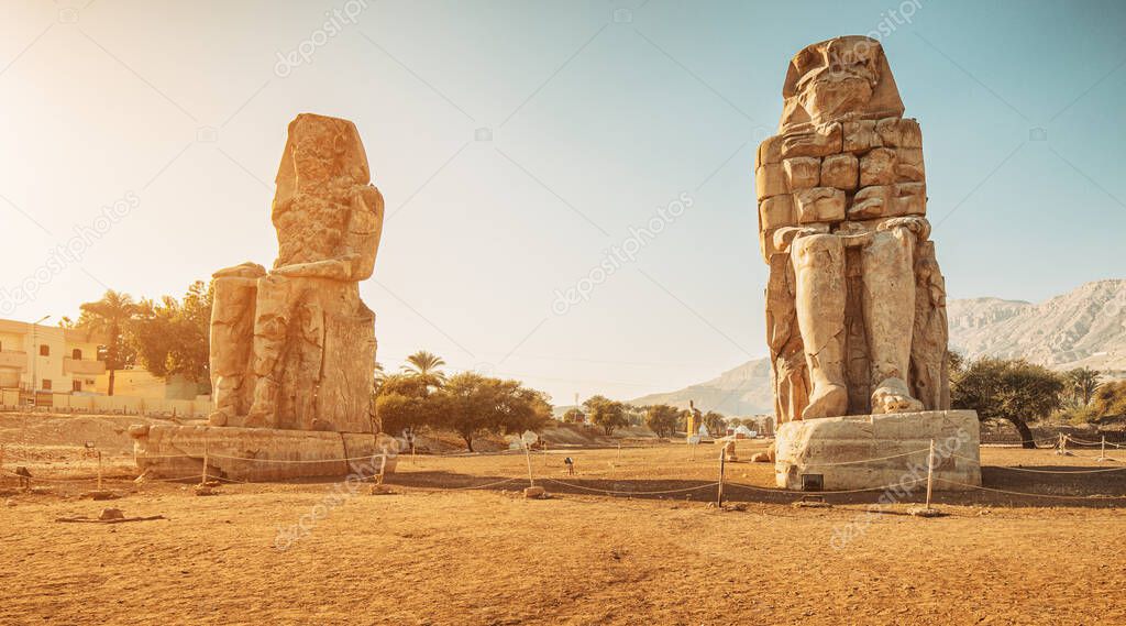Famous two Colossi of Memnon - massive ruined statues of the Pharaoh Amenhotep III. Travel and tourist landmarks near Luxor, Egypt
