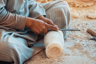 Close-up of artisan hands carving a stone souvenir for sale to tourists. Craft and handmade concept.