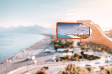 Gezgin blogcu kız, Türkiye 'nin Antalya kentindeki ünlü Konyaalti plajının yeni pahalı akıllı telefonunun kamerasında yüksek kaliteli ve canlı fotoğraflar çekiyor.