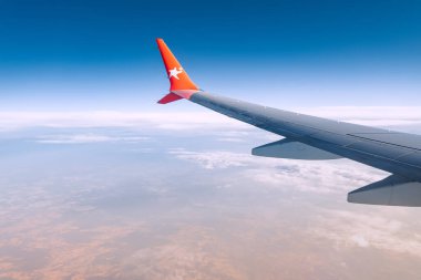 20 Temmuz 2022, Antalya, Türkiye: Kanatlı bir havayolu logosu. Tatildeki bir uçuş sırasında pencereden uçağın kanat manzarası. Yakıt ekonomisi için güzel gökyüzü ve kıvrımlı kanat