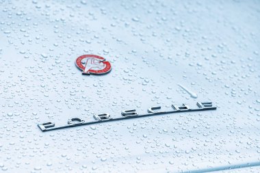 21 Temmuz 2022, Düsseldorf, Almanya: Yağmurlu bir arabanın kaputunda eski zamanlardan kalma Porsche logotype. Klasik araba stili