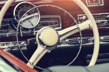 Dümeni ve gösterge paneli olan eski moda bir arabanın içi.