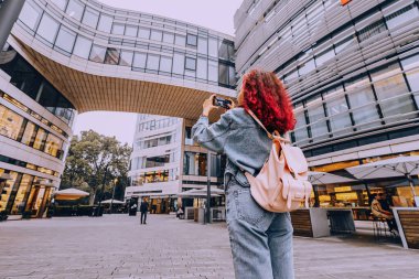 21 Temmuz 2022, Düsseldorf, Almanya: Turist kız ünlü Ko Bogen modern mimari binasında akıllı telefonla fotoğraf çekiyor.