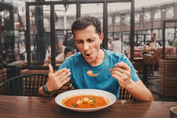 Мужчина Пробует Острый Горячий Красный Суп Ресторане Реагирует Смешно Эмоционально — стоковое фото
