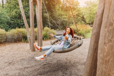 Mutlu kız çocukluğa düştü, eğleniyor ve çocuklar için çocuk parkında salıncakta sallanıyor. Çocukçuluk ve kişilik ve neşe psikolojisi