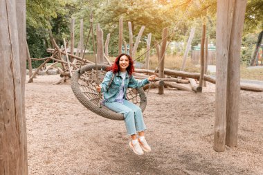 Mutlu kız çocukluğa düştü, eğleniyor ve çocuklar için çocuk parkında salıncakta sallanıyor. Çocukçuluk ve kişilik ve neşe psikolojisi