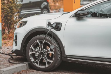 Modern bir elektrikli araba otoparkta şarj edilir. Çevresel farkındalık ve yeşil ulaşım ve yenilenebilir enerji kaynaklarına geçiş