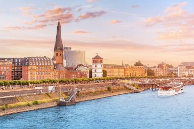 Düsseldorf şehrinin tanınabilir mimari kuleleri ve tüm Almanya 'nın ulaşım suları - Ren Nehri, büyük mavnalar, küçük gemiler ve botlar arasında koşuşturuyor..