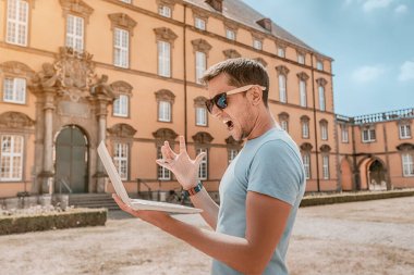 Kızgın ve hayal kırıklığına uğramış erkek öğrenci başarısız üniversite sınavlarının sonuçlarını bir dizüstü bilgisayardan kontrol ediyor.