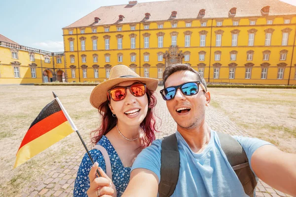 Two happy Travel bloggers takes selfie photos with german flag on the smartphone of the Osnabruck university campus in old town, Germany