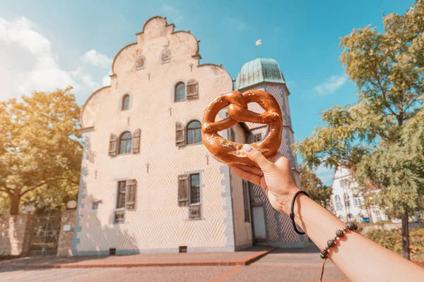 Main Féminine Avec Bretzel Traditionnel Allemand Sur Fond Vieux Bâtiment — Photo