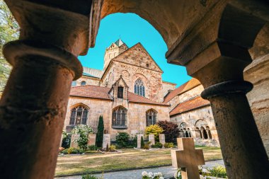 24 Temmuz 2022, Osnabruck, Almanya: Kemerleri ve kolonları olan bir ortaçağ manastırının iç avlusu. Küçük bir kilise mezarlığı.