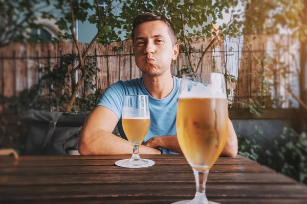 Funny drunk man drinks freshly brewed light beer from glasses in a bar or pub or a German beer garden
