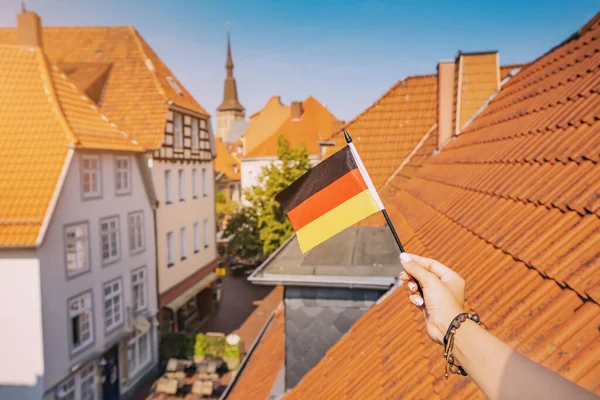 Ruka Držící Německou Vlajku Proti Oranžovým Střechám Starého Města Osnabruck — Stock fotografie