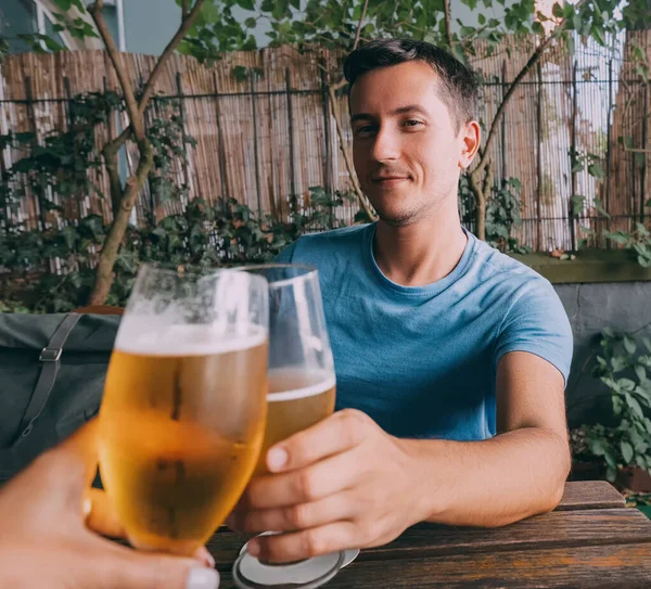 Funny drunk man clink freshly brewed light beer glasses in a bar or pub or a German biergarten