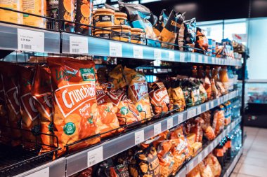 24 Temmuz 2022, Osnabruck, Almanya: Dükkanda çeşitli cips çeşitleri ve diğer fast food atıştırmalıkları.