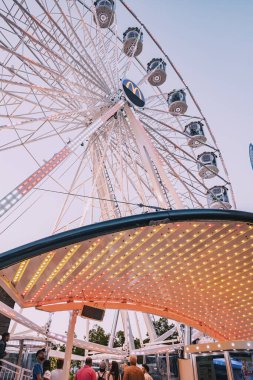 24 Temmuz 2022, Osnabruck, Almanya: Tarihi şehir merkezinde katedralin yanında dönme dolap bulunan lunapark ve eğlence parkının günbatımı