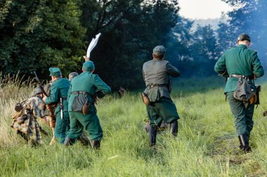 Porabka, Polonya, 07 Ağustos 2021: İkinci Dünya Savaşı 'ndan kalma savaşın yeniden inşası. Alman askerleri ellerini havaya kaldırdı ve beyaz bayrak Amerikan askerlerine teslim oldu. Tarihi yeniden yapılandırma.