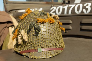 An M1 US infantry helmet from the Second World War lies on the bonnet of a military vehicle. clipart