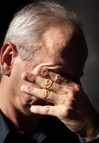 Oudere man met gezicht gesloten met de hand — Stockfoto