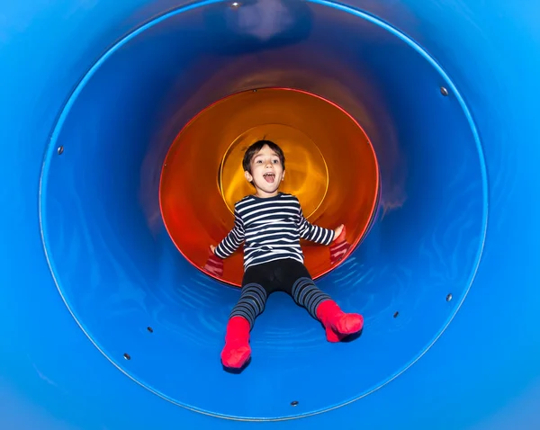 Alegre niño deslizándose en tubo de diapositiva — Foto de Stock