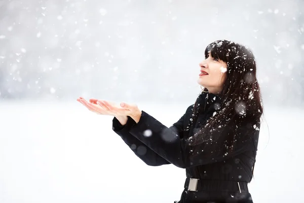 Ung kvinna fångster snöflingor — Stockfoto