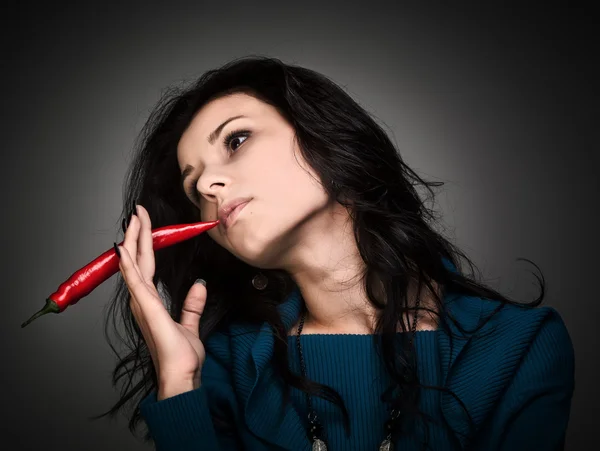 Mulher segurando pimenta vermelha quente na boca — Fotografia de Stock