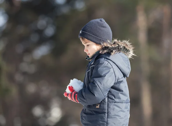 Söt pojke leker med snö — Stockfoto