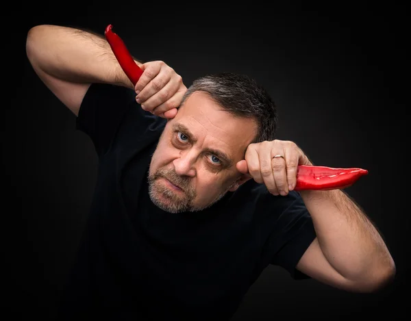 Älterer Mann hält zwei rote Chilischoten in der Hand — Stockfoto