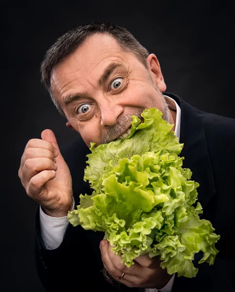 Homem segurando e comendo alface — Fotografia de Stock