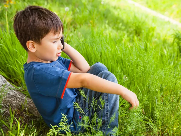 Menino na grama verde falando no telefone celular — Fotografia de Stock