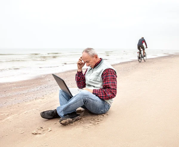 Old man with notebook on beach — Stock Photo, Image