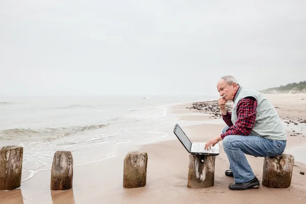 Gubbe med anteckningsboken på stranden — Stockfoto