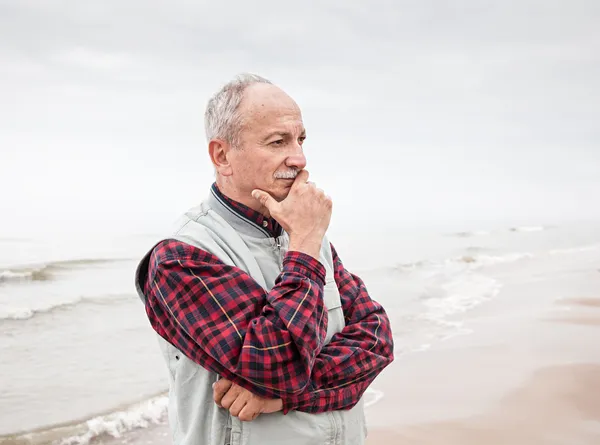 Thoughtful elderly man standing on the beach — Stock Photo, Image